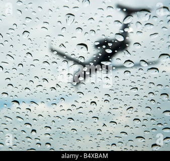 Low angle view of airplane through rain drops on window Stock Photo