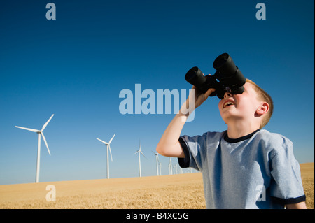 Boy on wind farm looking through binoculars Stock Photo