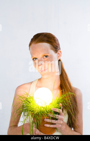 woman with energy saving light bulb in plant Stock Photo