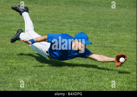 Baseball player diving to catch baseball Stock Photo