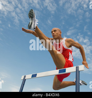 Runner jumping over hurdle Stock Photo