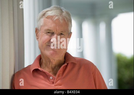Senior man leaning against column Stock Photo