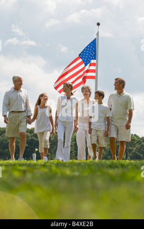 Multi-generational family walking in front of American flag Stock Photo