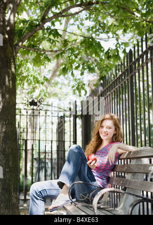 Woman relaxing on park bench Stock Photo