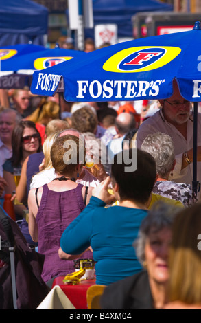 People sat drinking under FOSTERS umbrellas at Abergavenny Food Festival Stock Photo