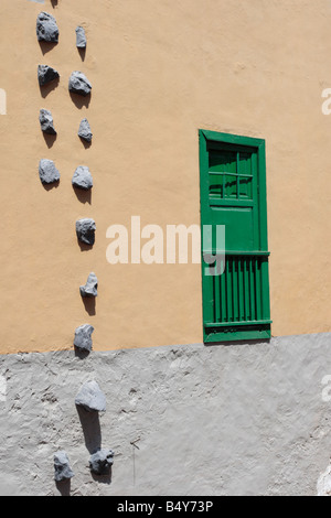 Wall with typical style of window and shutters and stones embedded on side of house in Guia de Isora, Tenerife Stock Photo