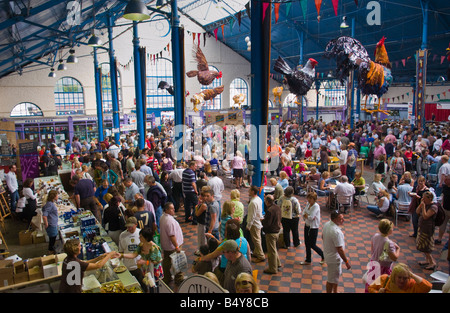 Crowds of people wander sit and browse stalls in the Market Hall during Abergavenny Food Festival Stock Photo