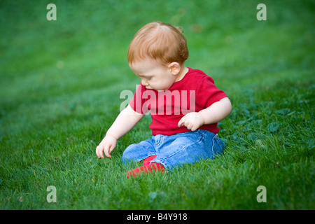 Young redheaded baby boy sitting outside on grass Stock Photo