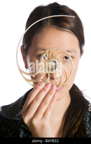 Asian woman holding a split nautilus shell in front of her face Stock Photo