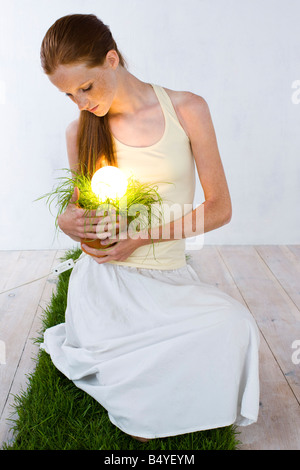 woman with energy saving light bulb in plant Stock Photo