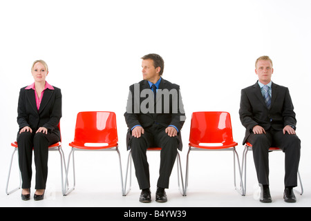 Three Business People Sitting On Red Plastic Seats Stock Photo
