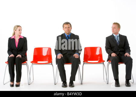 Three Business People Sitting On Red Plastic Seats Stock Photo