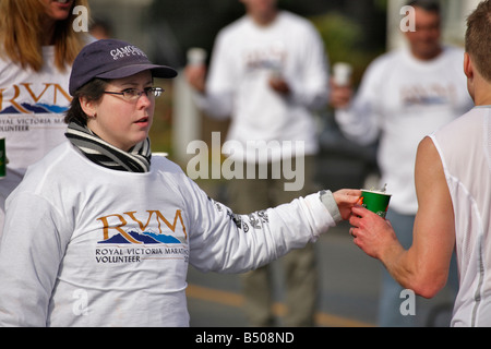 Royal Victoria marathon volunteer offering water to runner Victoria British Columbia Canada Stock Photo