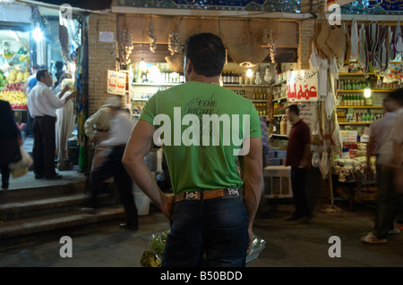A young man wearing a green T-shirt with 'For Right Or Wrong' printed on the back stands inside Tajrish Bazaar in northern Tehran, Iran. Stock Photo