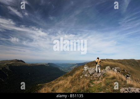 A tourist admiring the view of the Cantal region from the Puy Mary volcano Stock Photo