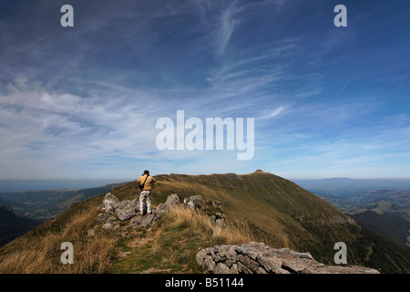 A tourist admiring the view of the Cantal region from the Puy Mary volcano Stock Photo