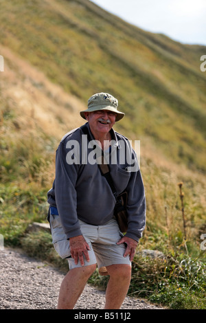 An elderly gentleman holds his legs after descending from the Puy Mary. Stock Photo