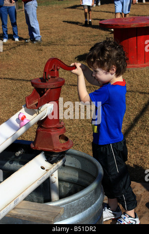 Child playing game with pump on farm.  Dixie, Louisiana, USA (Caddo Parish). Stock Photo