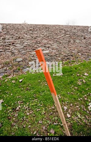 A wooden stake painted red on the top stuck into the ground Stock Photo