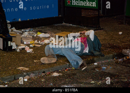 A drunken young woman lies in the filth left after the festival Stock Photo