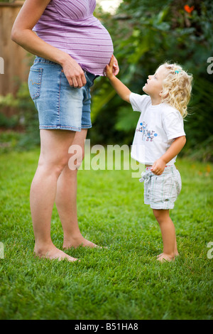 Girl Touching Pregnant Mother's Belly Stock Photo