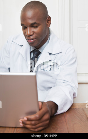 Physician Sitting Behind Desk Working on Laptop Stock Photo