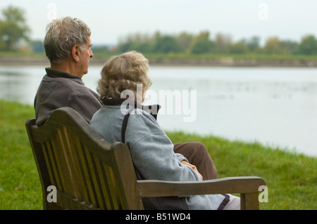 old age pensioners resting on a wooden bench overlooking a reservoir Stock Photo