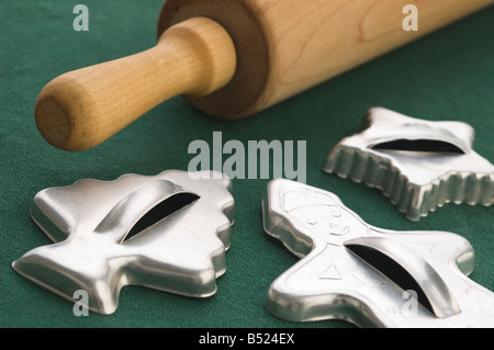 Vintage tin Christmas cookie cutters and wooden rolling pin on green background Stock Photo