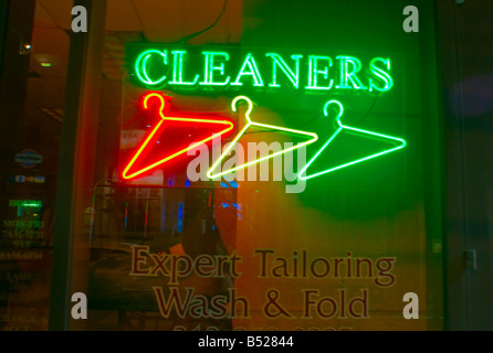 Three neon clothes hangers in NYC dry cleaners laundry store window. Stock Photo