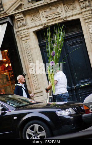 Man carrying large vase of flowers along the street Rue des Archives, Paris, France. Stock Photo