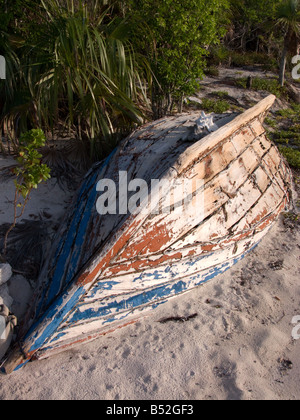 a wooden dinghy sits upside down on the beach in waderick wells exumas bahamas Stock Photo