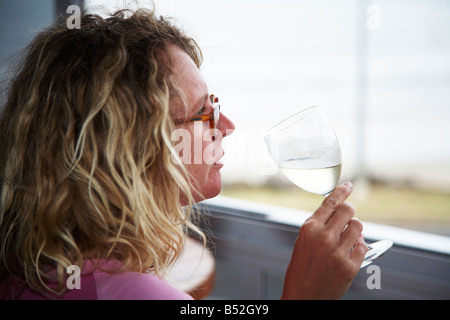 woman sipping glass of wine on balcony over looking the sea Stock Photo