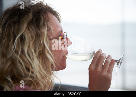 woman sipping glass of wine on balcony over looking the sea Stock Photo