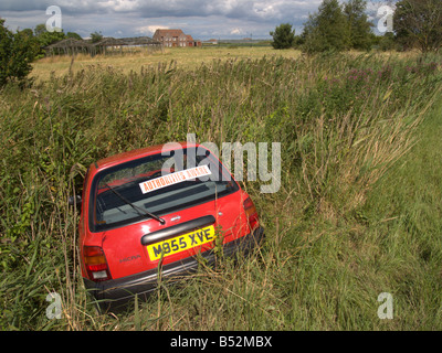 road traffic car accident rta skidded off road red car field ditch the fens england uk europe Stock Photo