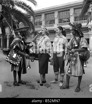 French actresses buy a drink of water from a local vendor in the town of Marrakech during their visit to Morocco. December 1952 Stock Photo