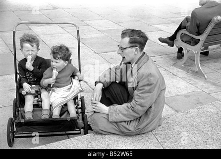 Holiday scenes. in and around Hastings. Two young boys in their pram enjoy a holiday ice cream as dad looks on.  June 1952 C2779 Stock Photo