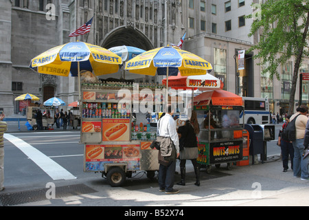People buying a pretzel from a hot dog vendor in Midtown Manhattan. next to them is a vendor selling candied nuts. New York, May 4, 2008 Stock Photo