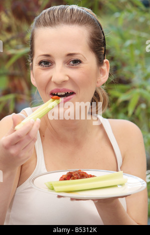 Young Woman Eating Celery and Salsa Model Released Stock Photo