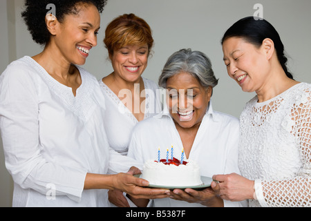 Friends surprising African woman with birthday cake Stock Photo
