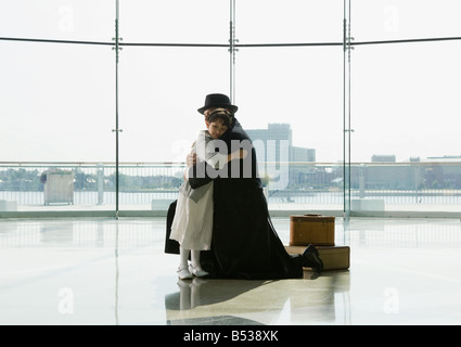 Hispanic father hugging daughter in airport Stock Photo