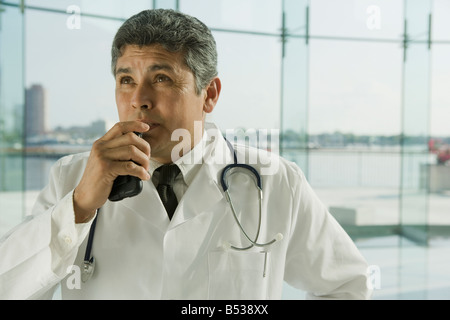 Hispanic doctor in lab coat speaking into dictaphone Stock Photo