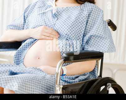 Pregnant Asian woman sitting in wheelchair at hospital Stock Photo