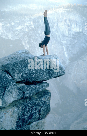 Performing a handstand on 'Overhanging Rock' at Glacier Point, Yosemite National Park, California Stock Photo