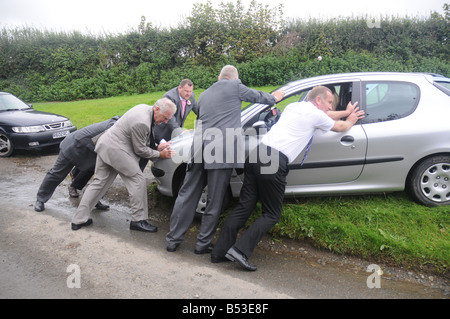 A group of men at a wedding push a broken-down car Stock Photo