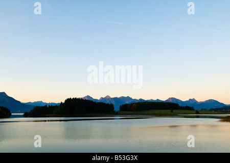 Forggensee lake at dawn with Allgäu Alps mountains rising in distance Bavaira, Germany Stock Photo