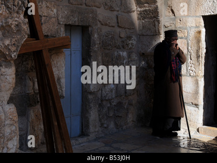 An Ethiopian Priest stands quietly in the sparce courtyard of the Church of the Resurrection in Jerusalem's Old City. Stock Photo