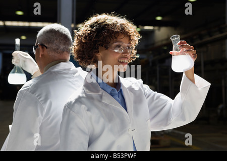 African scientists examining beakers of liquid in factory Stock Photo