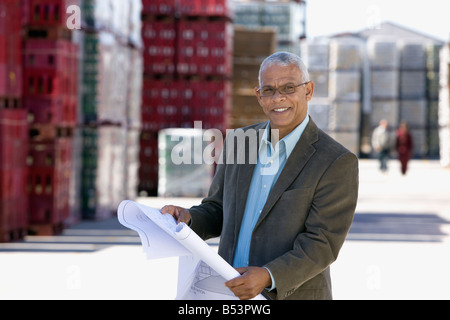 African architect reviewing blueprints at factory Stock Photo