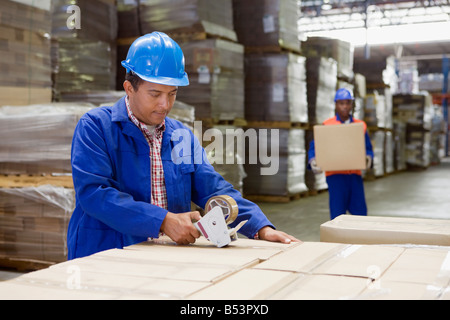 African worker taping boxes in warehouse Stock Photo
