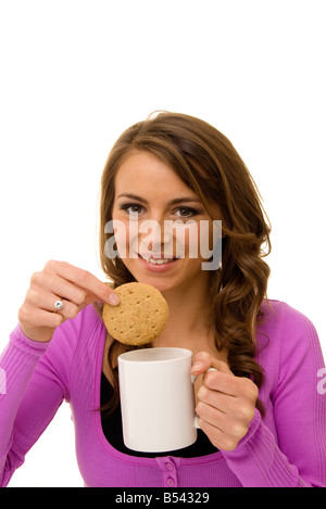 woman dunking a biscuit in a cup of tea Stock Photo